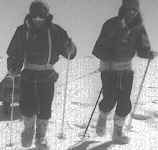 Two men pull a sledge by waist harnesses.